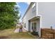 View of the home's siding, stone patio with grill, and spacious grassy backyard with partial fence at 7623 Rathburn Ln, Charlotte, NC 28277
