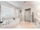 Relaxing bathroom featuring a garden tub, glass shower, white cabinets, and a window at 7623 Rathburn Ln, Charlotte, NC 28277