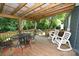 Covered deck with wood floor, metal table and chairs, and white rocking chairs at 792 W Nc Hwy 150 St, Lincolnton, NC 28092