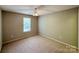 Bright bedroom featuring a ceiling fan, large window, neutral walls and carpeted floors, providing comfort at 9730 Elizabeth Townes Ln, Charlotte, NC 28277