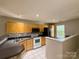 Bright kitchen featuring wood cabinets, black countertops, and views into the living area at 9730 Elizabeth Townes Ln, Charlotte, NC 28277
