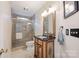 Well-lit bathroom featuring a glass shower, vanity with decorative mirror, and neutral tile at 140 Quiet Cove Rd, Mooresville, NC 28117