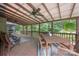 Covered deck area with wood furniture, ceiling fans, and overlooking a wooded backyard at 140 Quiet Cove Rd, Mooresville, NC 28117