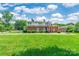 Backyard view of house with white trim, brick exterior, green grass, and bright skies at 15 Kings Mountain St, York, SC 29745