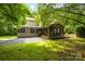 Backyard view featuring a screened porch, gravel patio, and well-maintained lawn surrounded by trees at 2156 Wedgewood Dr, Matthews, NC 28104