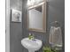 Modern half bathroom featuring a gray wall color, silver framed mirror, and a sleek pedestal sink at 2156 Wedgewood Dr, Matthews, NC 28104