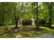 Exterior shot of home, screened porch, and yard surrounded by mature trees for privacy at 2156 Wedgewood Dr, Matthews, NC 28104