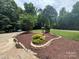 Beautifully landscaped front yard featuring a manicured lawn, stone retaining wall, and decorative shrubs at 2156 Wedgewood Dr, Matthews, NC 28104