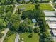 An aerial perspective reveals a house enveloped by trees and greenery, flanked by buildings, roads, and open land at 4534 Pebblebrook Sw Cir, Concord, NC 28027