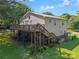 The house has a large wooden deck and stairs, lush greenery, and a cozy, shaded area underneath the deck at 4534 Pebblebrook Sw Cir, Concord, NC 28027