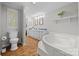 This bathroom features a whirlpool tub, toilet, and vanity with double sinks and wood-look floors at 4534 Pebblebrook Sw Cir, Concord, NC 28027