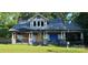 Overgrown property with a rundown two-story home featuring a covered porch and visible damage at 619 N Main St, Landis, NC 28088
