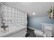 Compact bathroom featuring a marble-top vanity, toilet, and shower with a light blue checkered curtain at 704 N Main Ave, Newton, NC 28658