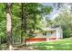 View of the back of a two story home in a wooded lot with a red basement and light siding at 7154 Woodcock Trl, Stanley, NC 28164