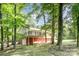 Two story home features a deck, red basement, and multiple garage doors in a backyard wooded lot at 7154 Woodcock Trl, Stanley, NC 28164
