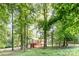 Wooded lot with a two story home featuring a large deck and a red basement, providing shade and privacy at 7154 Woodcock Trl, Stanley, NC 28164