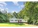 Charming single-story home with a manicured lawn and red shutters, surrounded by lush trees at 7154 Woodcock Trl, Stanley, NC 28164