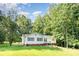 Inviting one-story home with a lush front lawn, mature trees, and blue sky at 7154 Woodcock Trl, Stanley, NC 28164