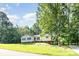 Inviting one-story home with a lush front lawn, pathway and mature trees at 7154 Woodcock Trl, Stanley, NC 28164
