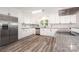 Modern kitchen featuring stainless steel appliances, white cabinets, and laminate flooring at 7154 Woodcock Trl, Stanley, NC 28164