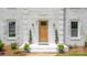 Charming white brick home entrance featuring a stylish wood door, modern lighting and greenery at 8337 Norcroft Dr, Charlotte, NC 28269