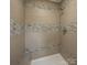Modern walk-in shower featuring neutral ceramic tile and a built-in bench at 8337 Norcroft Dr, Charlotte, NC 28269