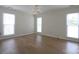 This bedroom boasts three bright windows, hardwood floors, and a modern chandelier, creating a comfortable and stylish space at 8829 Gelligum Dr, Charlotte, NC 28277