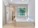 Bright bathroom features a soaking tub, glass shower, and large window at 8909 Elkins Park Dr, Matthews, NC 28105