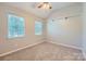 Cozy bedroom with plush carpeting, two windows providing natural light, and a ceiling fan at 8909 Elkins Park Dr, Matthews, NC 28105