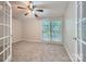 Bedroom with neutral carpet, large window, ceiling fan and glass panel door at 8909 Elkins Park Dr, Matthews, NC 28105