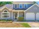 Inviting entrance with a glass front door, manicured shrubs, and a two-car garage at 8909 Elkins Park Dr, Matthews, NC 28105
