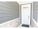 Inviting front entrance with gray siding accented by stone, leading to a bright white door at 12209 Riceland Way, Midland, NC 28107