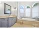 Luxurious bathroom featuring a soaking tub, custom vanity, and arched windows that provide ample natural light at 149 Vista Bluff Ln, Mooresville, NC 28117