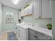 Laundry room with plants on top of the gray cabinets, window, and washer/dryer at 15211 Colonial Park Dr, Huntersville, NC 28078