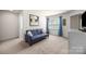 Cozy sitting room with neutral carpet, sofa, and bright window with blue curtains at 15211 Colonial Park Dr, Huntersville, NC 28078