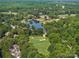 Stunning aerial view of a golf course surrounded by trees, a lake, and residential properties at 18800 Boundary Oaks Ct, Davidson, NC 28036