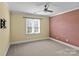 Bedroom featuring neutral carpet, ceiling fan, large window and textured accent wall at 18800 Boundary Oaks Ct, Davidson, NC 28036