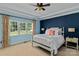 Bedroom featuring a decorative blue accent wall, plush carpet, and a large window at 18800 Boundary Oaks Ct, Davidson, NC 28036
