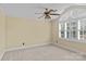 Bright bedroom featuring a ceiling fan, neutral carpet, and large arched window with shutter blinds at 18800 Boundary Oaks Ct, Davidson, NC 28036