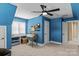 Blue bedroom offering a desk area, ceiling fan, large window and neutral carpet at 18800 Boundary Oaks Ct, Davidson, NC 28036