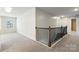 Upstairs hallway showcasing carpet, natural light, and staircase with dark brown railings and white trim at 2097 Saddlebred Dr, Iron Station, NC 28080