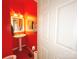 Vibrant half-bathroom with a pedestal sink, striking red walls, and modern fixtures at 3114 Luke Crossing Dr, Charlotte, NC 28226