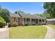 Inviting exterior of a brick home with a covered front porch, complemented by lush green landscaping and a curved walkway at 5006 Crooked Oak Ln, Charlotte, NC 28226