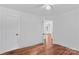 Bright bedroom features hardwood floors, white walls, and open doorway leading to another room at 564 Greenway Dr, Statesville, NC 28677