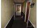 Hallway with dark carpet leads to a white door with window covering allowing bright sunlight to stream through at 5823 Rupert Ln, Charlotte, NC 28215