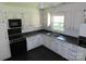 Traditional kitchen featuring contrasting black and white cabinets, dual basin sink, and modern appliances at 5823 Rupert Ln, Charlotte, NC 28215