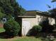 Exterior of an outbuilding or shed showing weathered pale yellow siding and white door surrounded by greenery at 5823 Rupert Ln, Charlotte, NC 28215