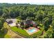 Stunning aerial view of a brick home with a pool and detached garage surrounded by lush greenery at 929 Blacksnake Rd, Stanley, NC 28164