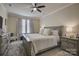 This bedroom features a ceiling fan, a large bed with neutral colored bedding, and natural light from the windows at 9507 Pointer Rd, Huntersville, NC 28078
