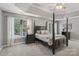 A traditional-style bedroom with a four-poster bed, carpet, and three large windows at 9735 Devonshire Dr, Huntersville, NC 28078